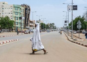 A woman walks across a road in Niamey on August 8, 2023.