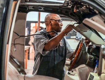 automotive technician working on the wiring of the inside of a vehicle