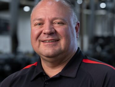 Headshot of a man in black with red highlights WyoTech polo shirt.