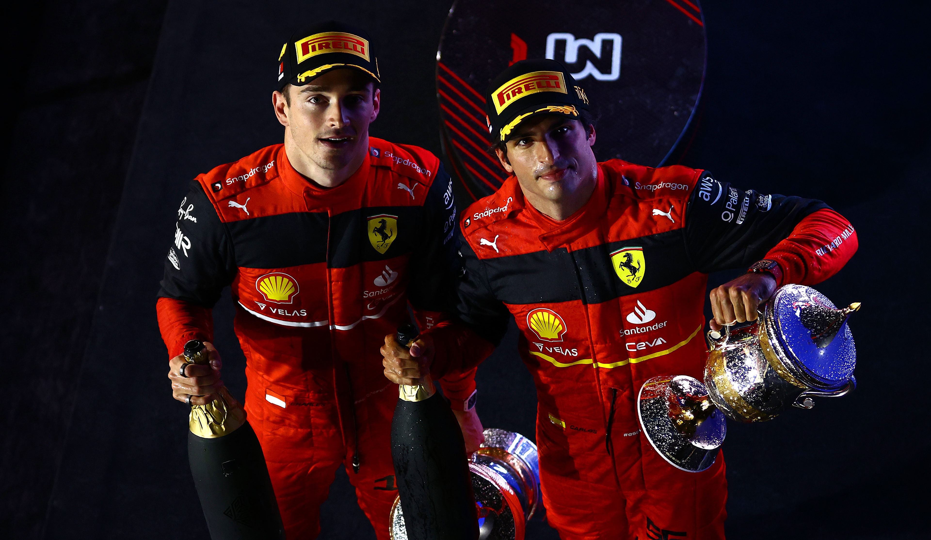 Ferrari race drivers Charles Leclerc and Carlos Sainz looking upward with champagne bottles celebrating their top-two finish in the F1 Bahrain GP