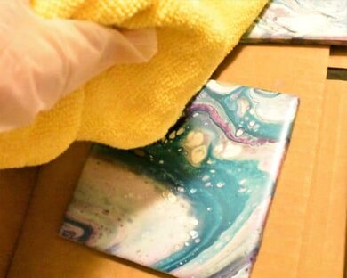 cleaning DIY coasters with microfiber towel, wearing gloves