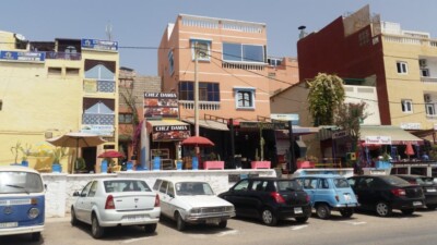 Niz malih restorana sa suncobranima i parkirani auti uz put