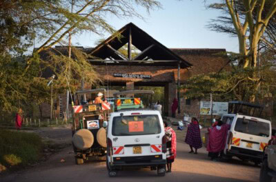 Safari vozila i meštani ispred kapije Masai Mara nacionalnog rezervata