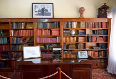 Enterijer stare biblioteke sa drvenim policama punim knjiga i pisaćom mašinom na stolu