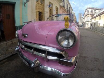 Roze oldtajmer parkiran uz stare kuće u uskoj gradskoj ulici
