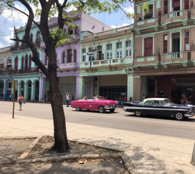 Roze kabriolet oldtajmer prolazi pored pastelnih fasada u Havani