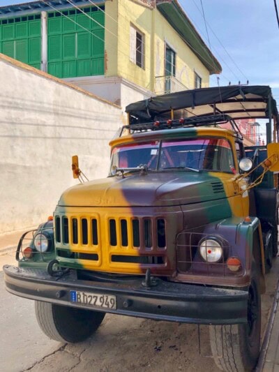 Stari kamion oslikan maskirnim šarama parkiran pored zida