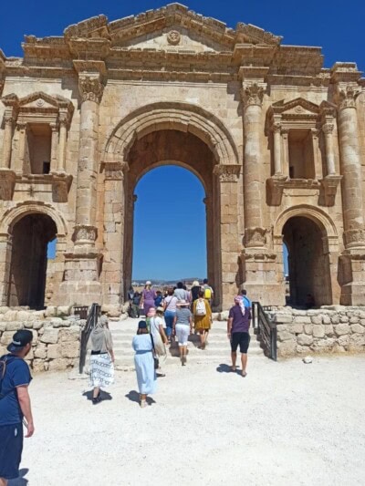 Rimska kapija sa turistima koji prolaze kroz veliki kameni luk u Jerašu