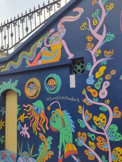 Šareni mural sa fantastičnim morskim bićima i natpisom na plavom zidu