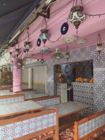 Bašta restorana sa orijentalnim mozaik lampama, pločicama i pomorandžama na tezgi