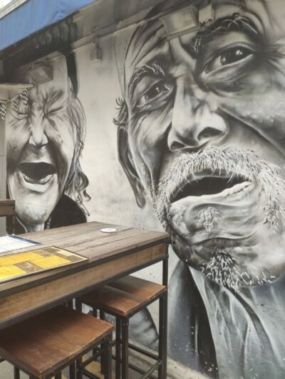Crno beli mural sa portretima dvojice staraca iznad stočića za ručavanje