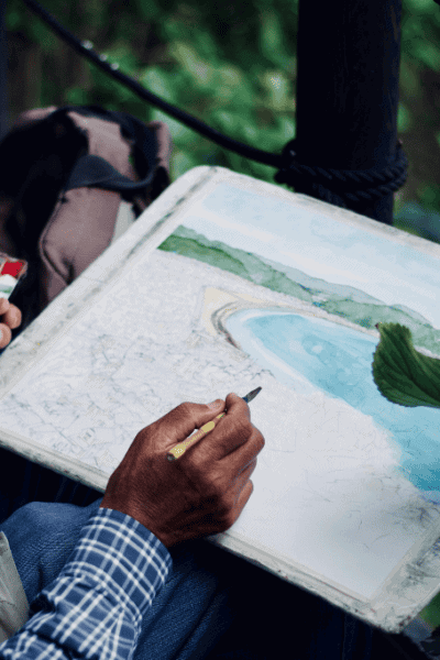 Person holidng a brush and creating an acrylic painting landscape