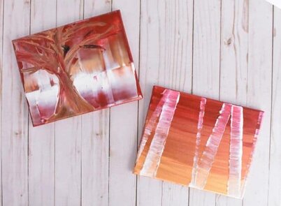 photo of two tree paintings, one lone tree and one forest of birch trees, both in gold, copper, red, and white tones