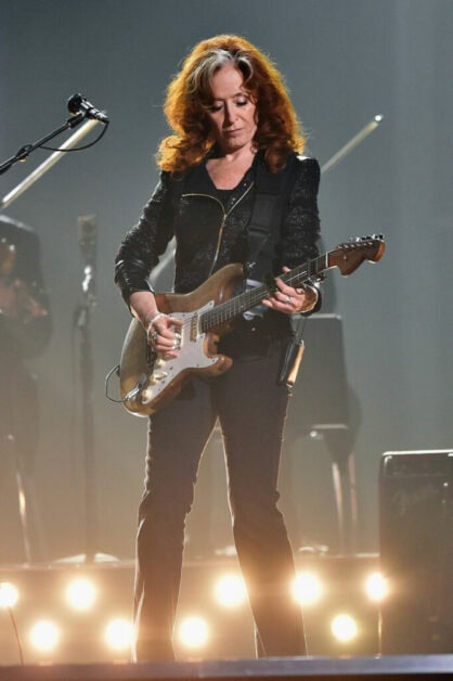 phot of Bonnie Raitt playing guitar on stage