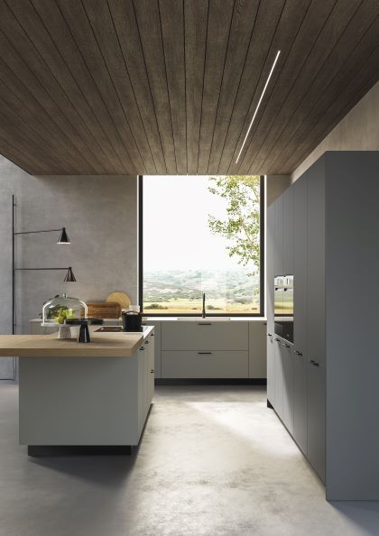 Cucina con isola in grigio chiaro, top in Okite e lavandino sotto finestra in loft