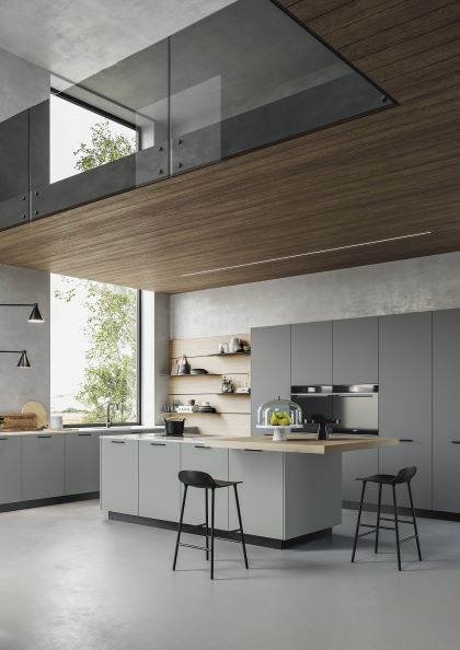 Cucina componibile moderna in grigio chiaro, con isola con fuochi e tavolo per colazione sotto soppalco in legno di olmo