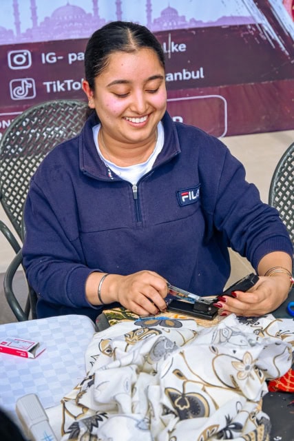 A smiling workshop facilitator works with fabric during the Frame and Fabric Workshop at Galleria.