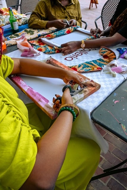 Several participants collaborate on colourful frame and fabric projects around a workshop table at Galleria.
