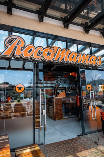 Glass restaurant entrance with large Rock Mama’s signage and branded star decals on the doors.