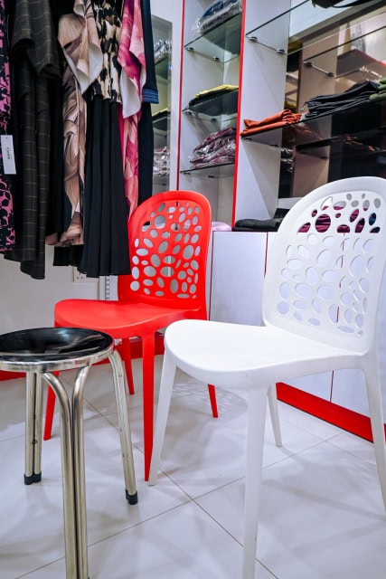Clothing shop interior with garment racks, glass shelves and chairs