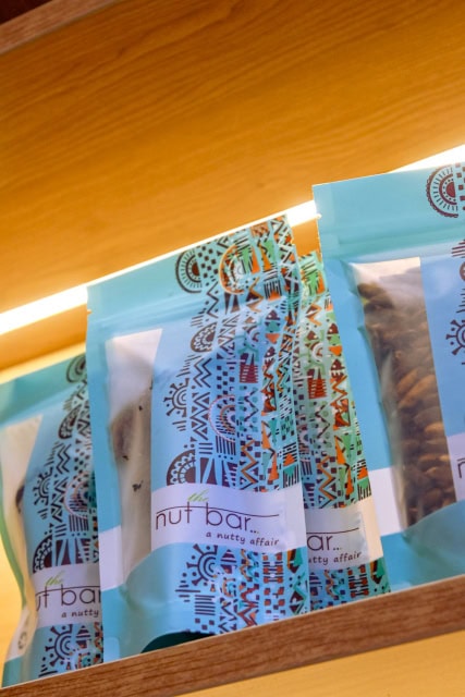 Blue patterned pouches of nut bar products displayed on a wooden shelf.