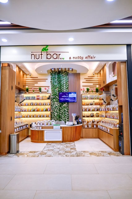 Storefront with nut bar signage, illuminated product shelves, and a central counter