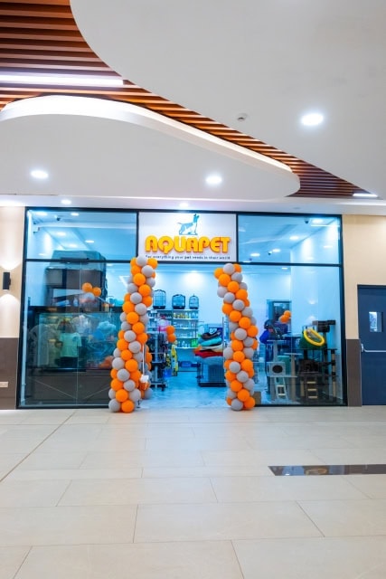 Glass-fronted AQUAPET store entrance with an orange-and-white balloon arch.