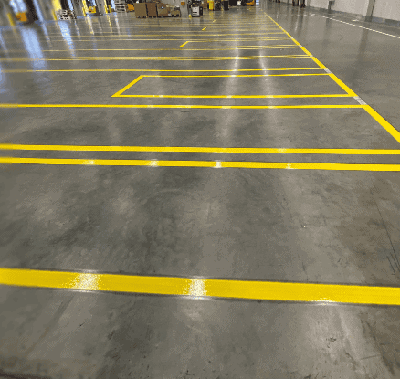 Gelbe Linien bilden strukturierte Lagerflächen mit rechteckigen Feldern in weitläufiger Industriehalle.