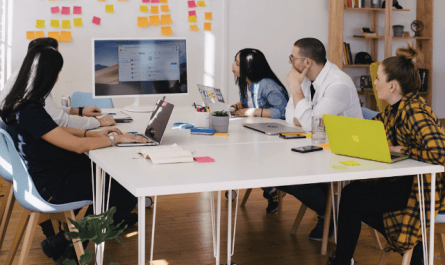 A team in an office discussing a knowledge management system during a meeting