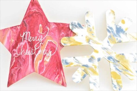 Two wooden Christmas Decorations decorated with acrylic pouring, one star and one snowflake