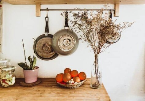 Pans hanging on wall, flowers in vase on table