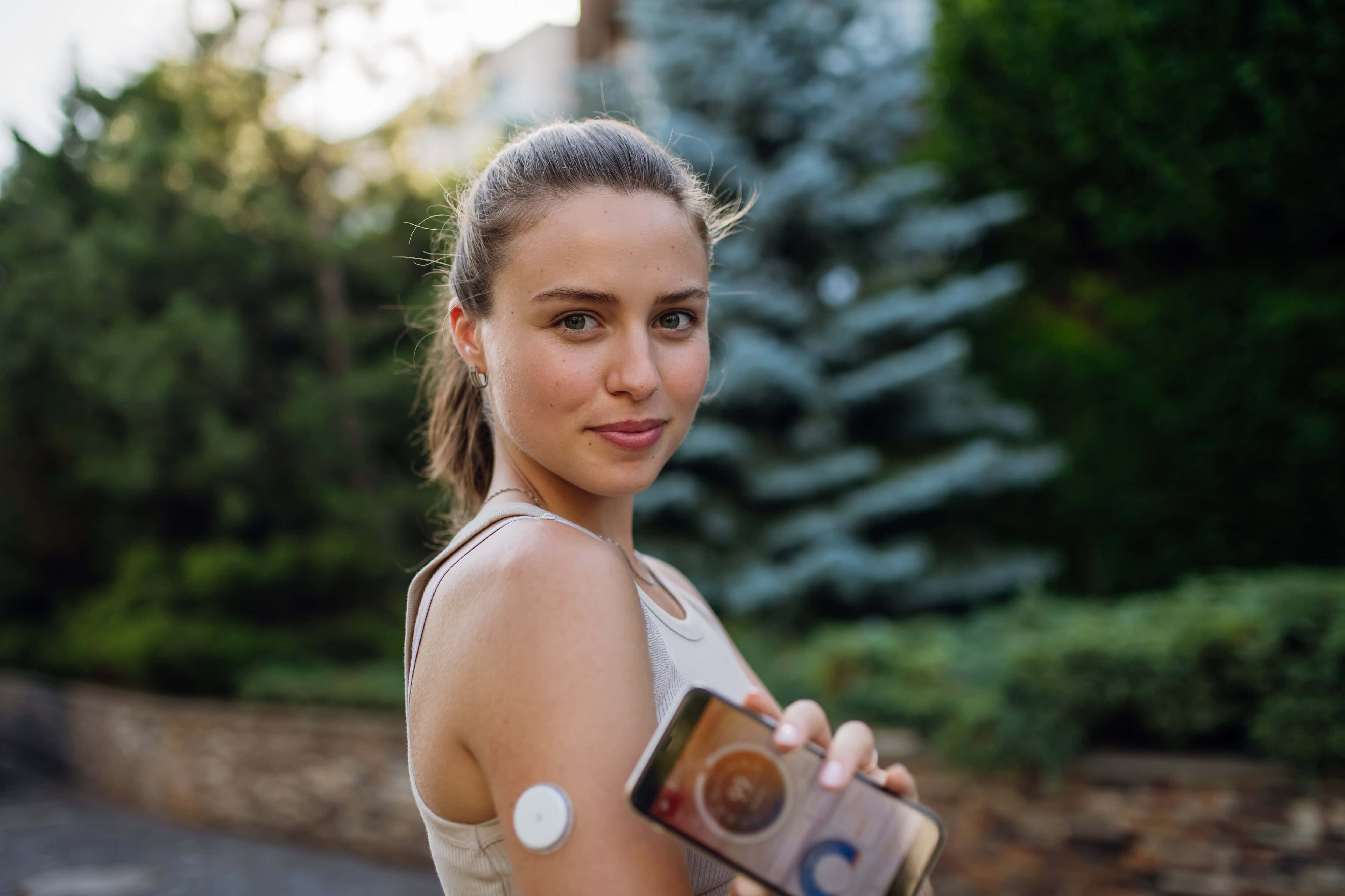 Woman with diabetes connecting her smartphone to continuous glucose monitor sensor before exercising