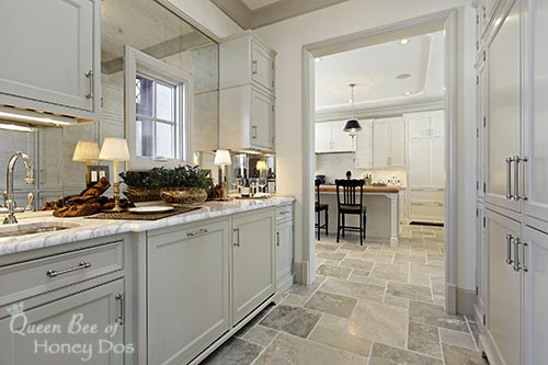 scullery with sage green cabinets and view of kitchen off the side