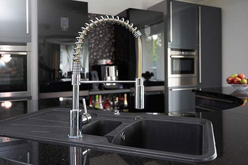 kitchen faucet set against black cabinetry