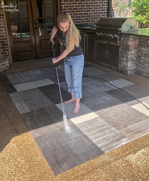 woman pressure washing a rug