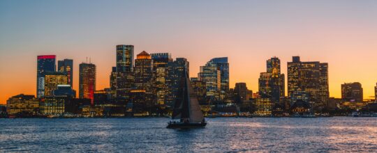 Boston skyline at sunset with a sailboat in the harbor