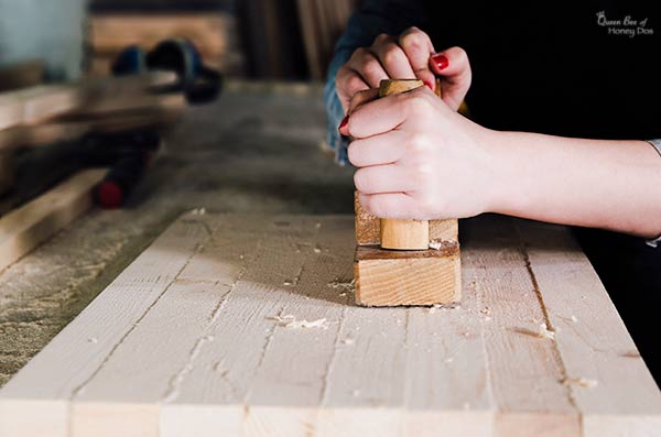 woman planing cutting board with wooden plane