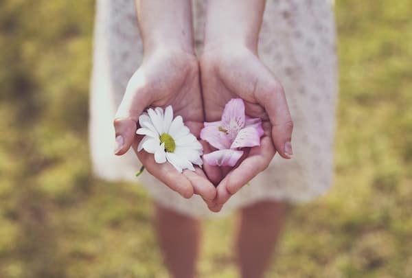 Woman being an empath, holding white and pink flowers in her palms.