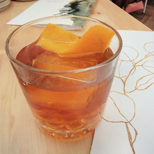 lowball glass with whiskey and orange peel called the Atria Old Fashioned