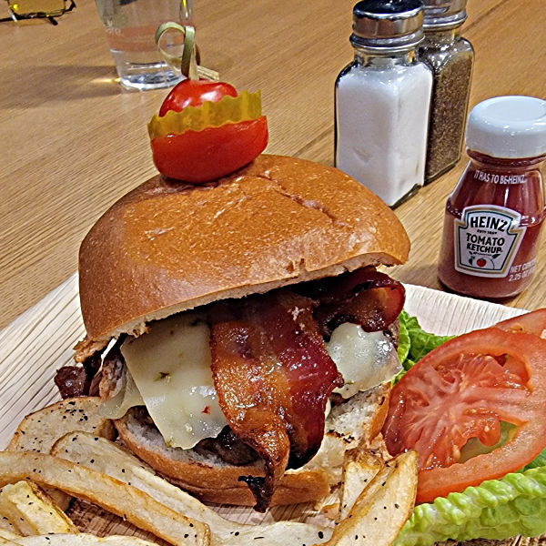 large hambuger on bun with fries and tomatoes, pepper jack cheese