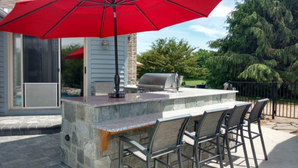 conventional l-shaped outdoor kitchen with an umbrella on the countertops