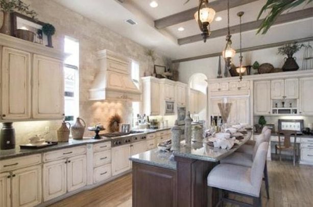 large traditional kitchen with yellow backsplash, bi-level island, and distressed white cabinet