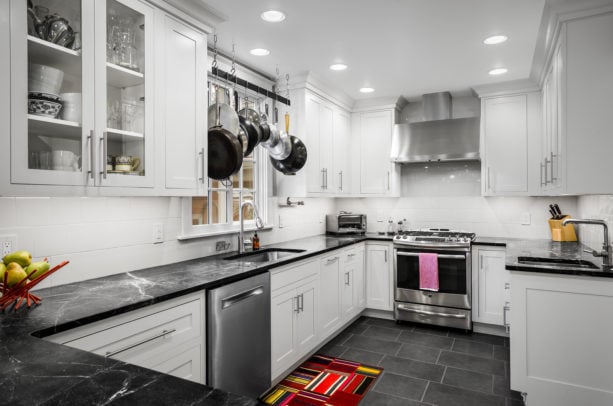 small yet classy kitchen with white cabinets and backsplash combined with ebony black countertops