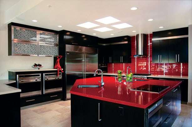 the combination between black cabinets and island with glossy red countertops and tiled backsplash