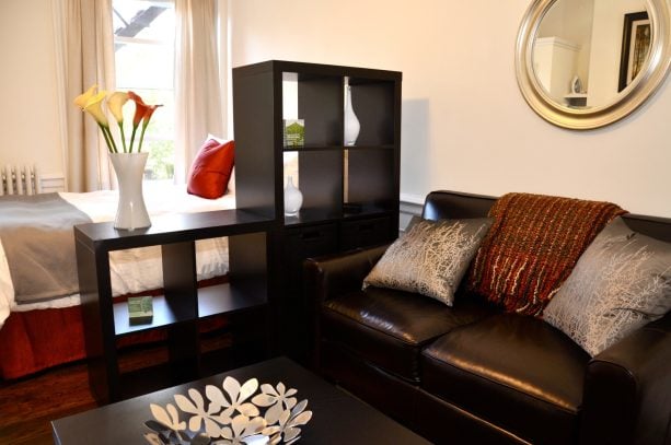 dark open shelves that match the leather couch in the living room as a room divider