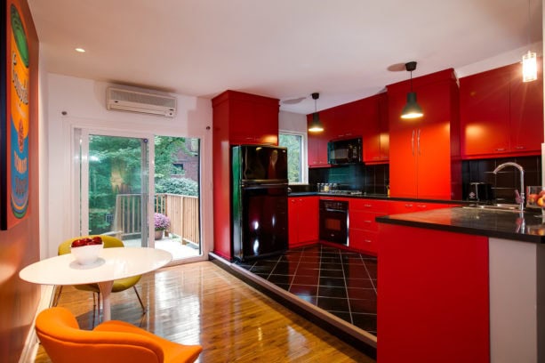 a contemporary red kitchen with black appliances