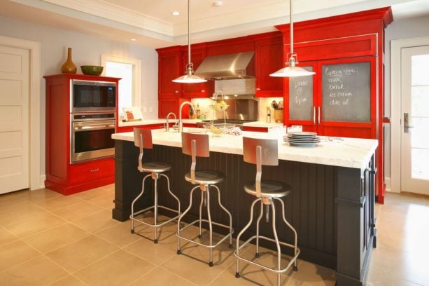 a set of red custom cabinets paired with black island in an eclectic kitchen