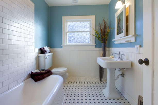 a traditional bathroom with monochrome style combined with blue wall and white-colored tub