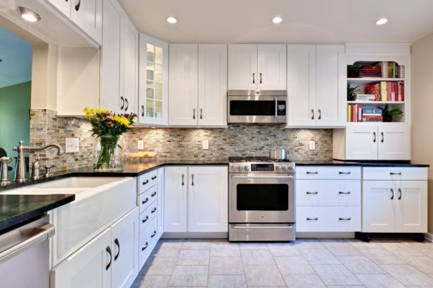 transitional u-shaped kitchen in monochromatic color featuring white cabinets and pebble black countertops