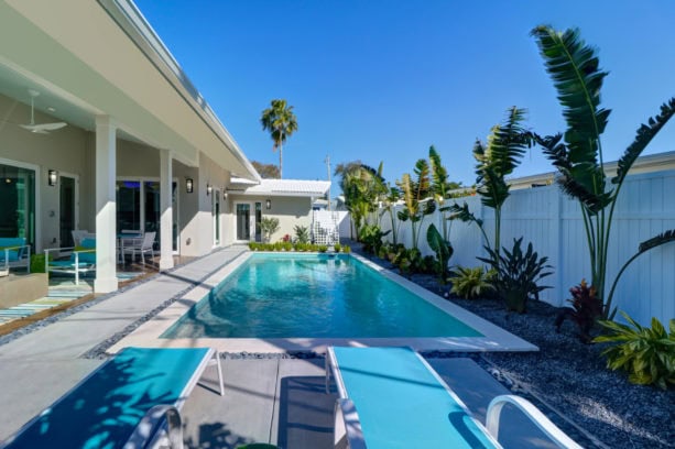 a contemporary pool surrounded with black river rock and stamped concrete slabs